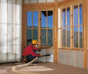 Worker installing insulation beneath a window.