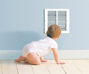 Baby crawling in front of an air vent.
