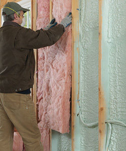 Worker installing flash and batt insulation.