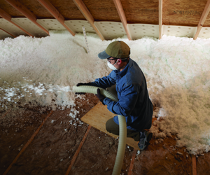 Worker installing blown-in insulation.