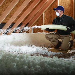 Worker spraying foam insulation inside an attic