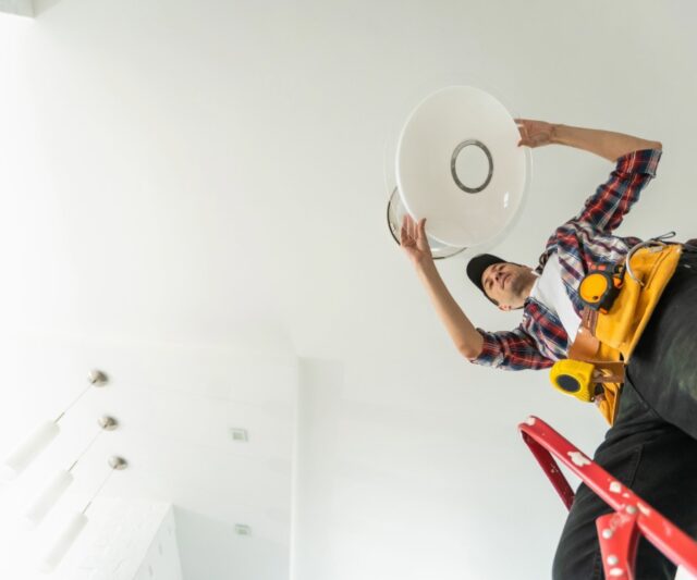 Electrician installing led light bulbs in ceiling lamp.
