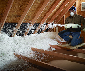 Worker installing loose-Fill insulation in an attic.