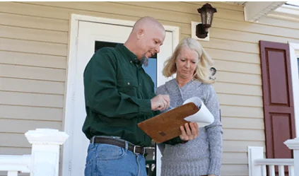 Male appraiser showing information on a clipboard to a female homeowner.