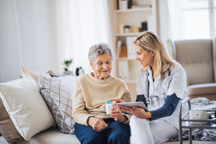 Home health aid visiting an older woman at home.