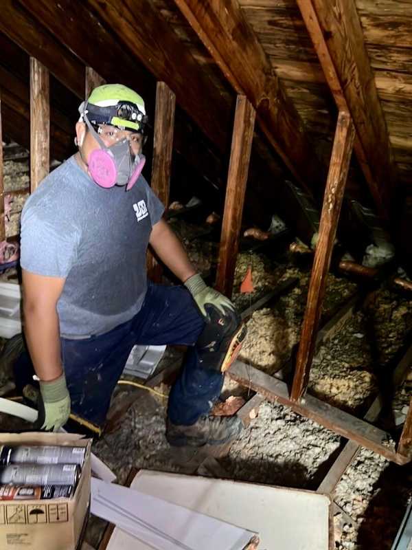 DeVere technician installing loose fiberglass insulation in attic.