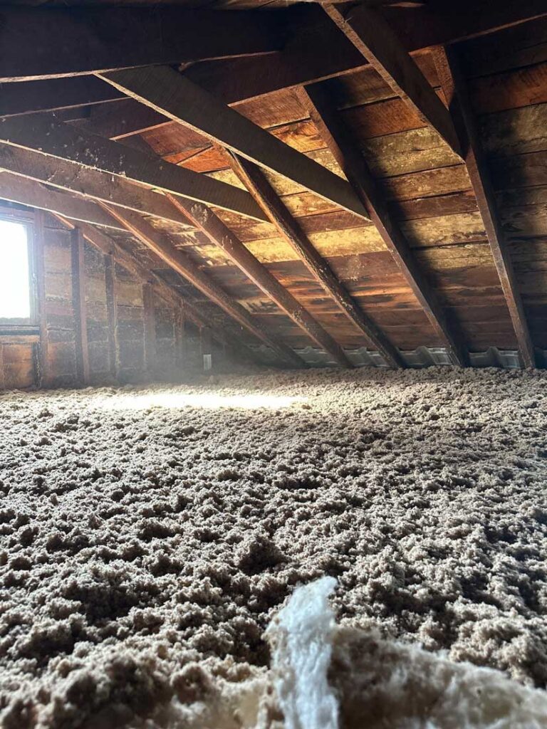 Cellulose blown insulation being installed in an attic by DeVere Insulation Home Performance, showcasing an efficient method for enhancing home energy efficiency and comfort.