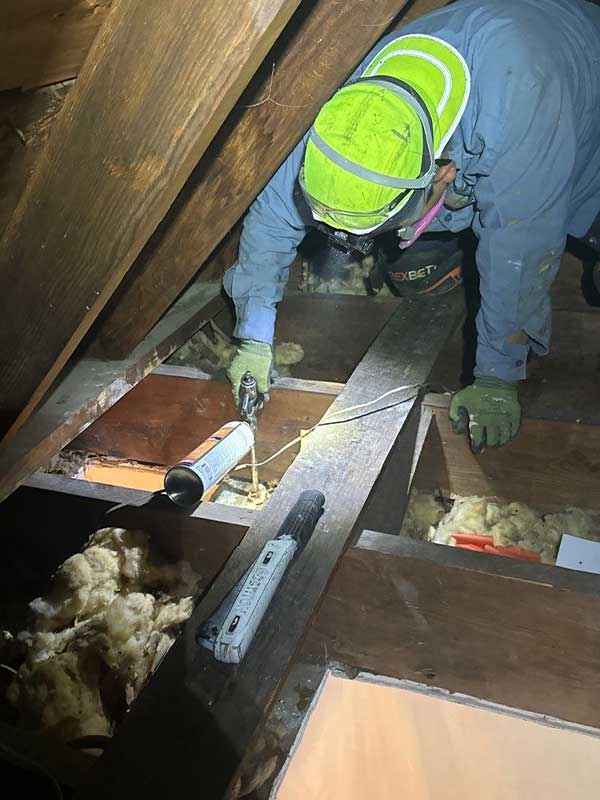 Close-up of air sealing process in attic: A close-up view of DeVere Insulation Home Performance's specialized foam being applied around attic framing and gaps to enhance insulation efficiency.