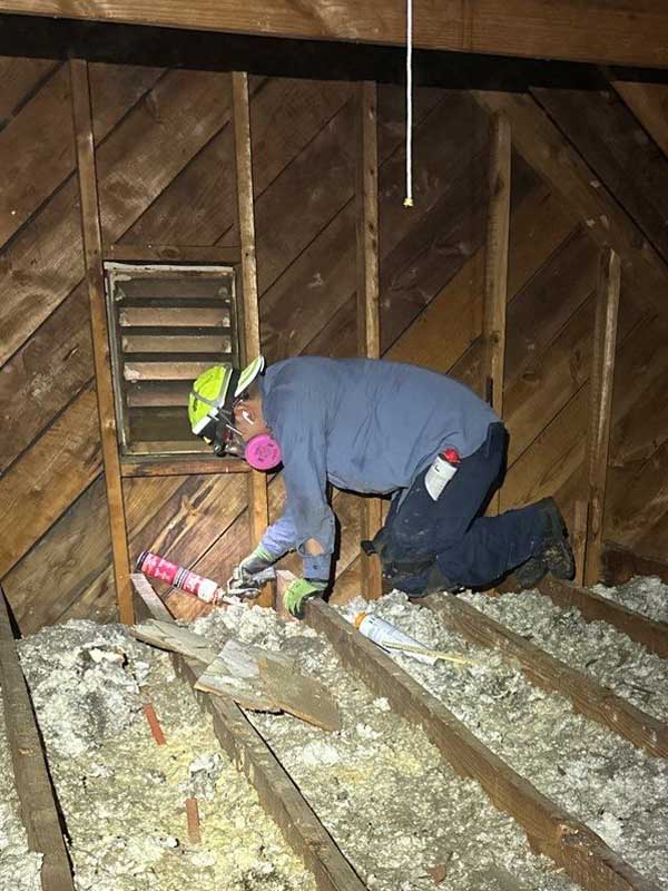 DeVere Insulation technician applying spray foam for air sealing in an attic to improve energy efficiency and prevent air leaks.