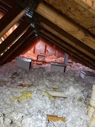 Recessed Light Insulation Process: A technician ensuring that recessed light covers in the attic are properly sealed and insulated to prevent drafts and optimize home energy performance.