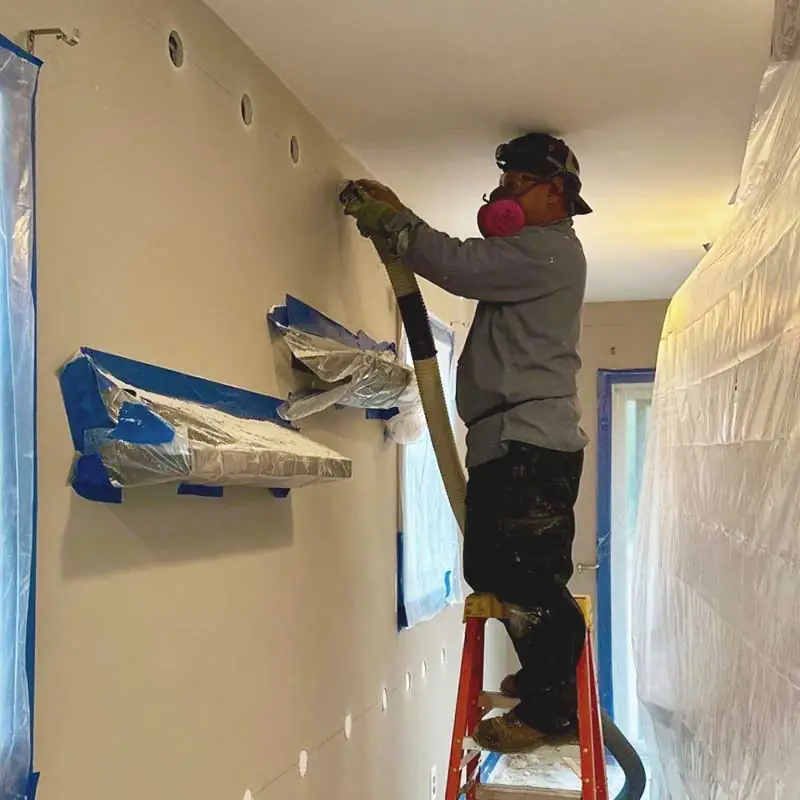 Close-up of wall insulation being expertly installed in a residential home. Improve your home’s thermal performance and reduce energy costs with DeVere Insulation's services.