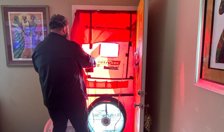 echnician performing a blower door test in a residential home using a Retrotec system to measure air leakage and energy efficiency.