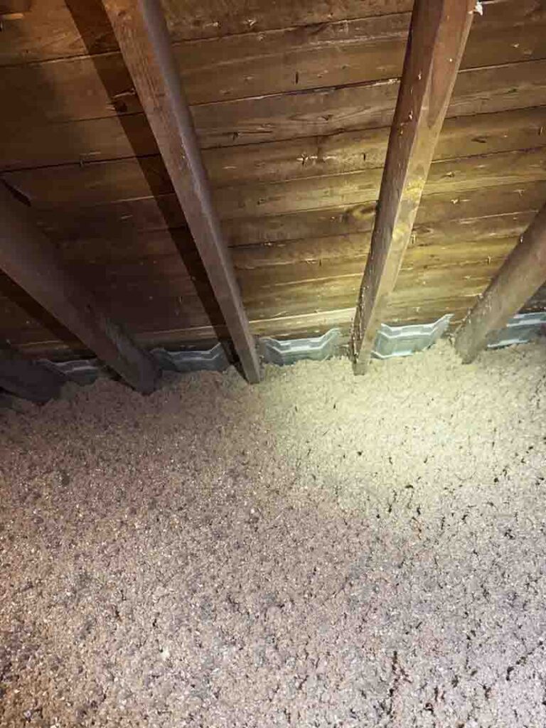 Dense-blown cellulose insulation installed in attic space with visible vent baffles for airflow.