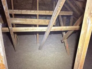Attic floor filled with an even layer of loose‑fill cellulose insulation between roof trusses.