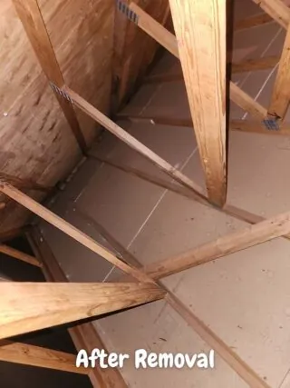 Clean attic space after batt insulation removal, exposing wood rafters and ductwork.