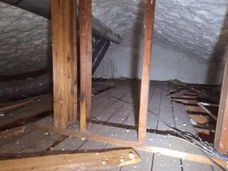 Attic space with spray foam on the roof deck and existing plank sub‑floor visible below.