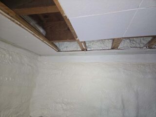 Rim‑joist cavities spray‑foamed above a basement wall with foam‑board inserts.