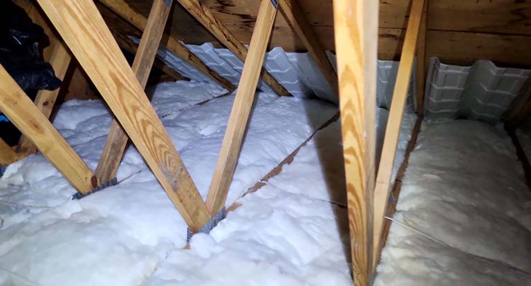 Ceiling insulated with fiberglass batt insulation covered by a self-adhered clear plastic vapor barrier to reduce air infiltration and protect insulation.
