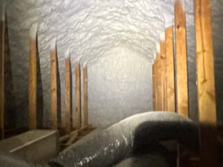 Narrow attic cavity with spray‑foam roof deck and HVAC flex duct routed through the space.